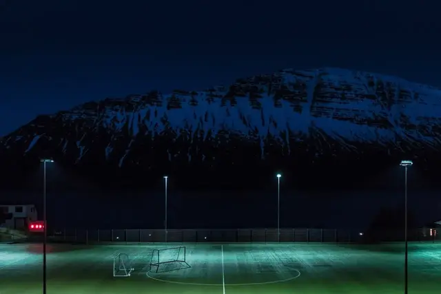 Kunstgrasveld met brandende lichtmasten in de avond